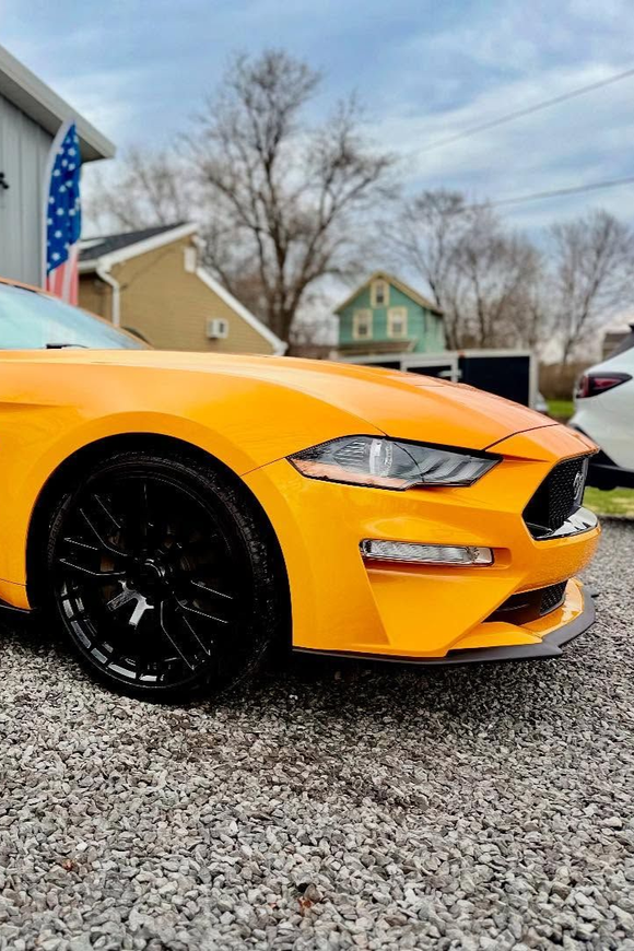 A man is cleaning the wheel of a black car with a sponge.