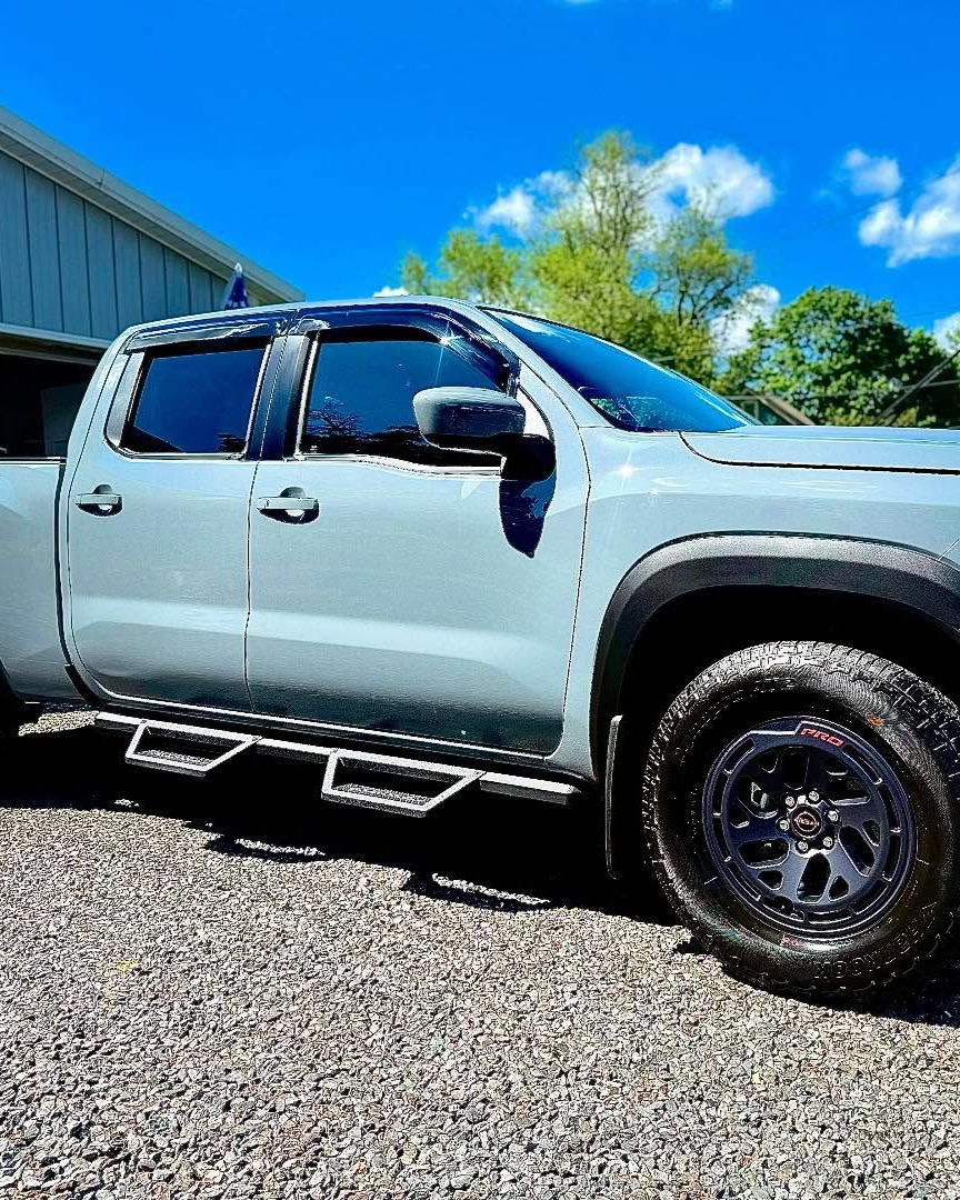 A person is using a blue squeegee to remove plastic from the hood of a car