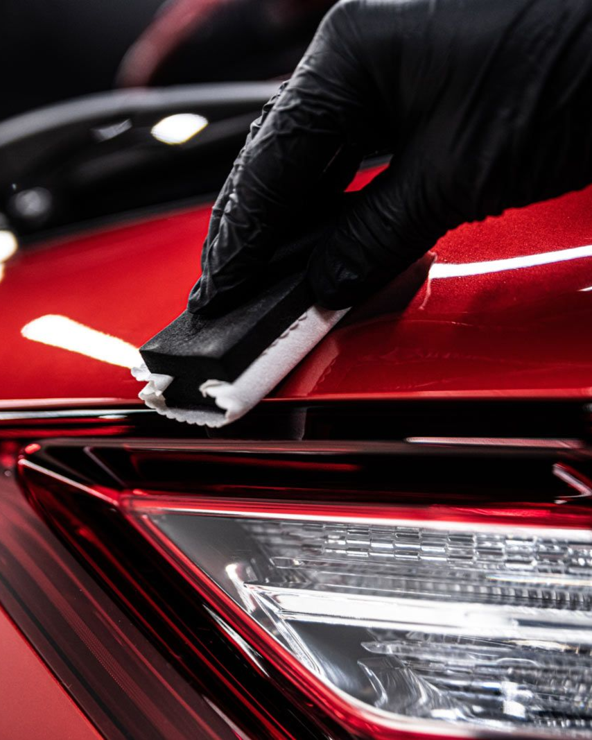 A person is washing a car wheel with foam