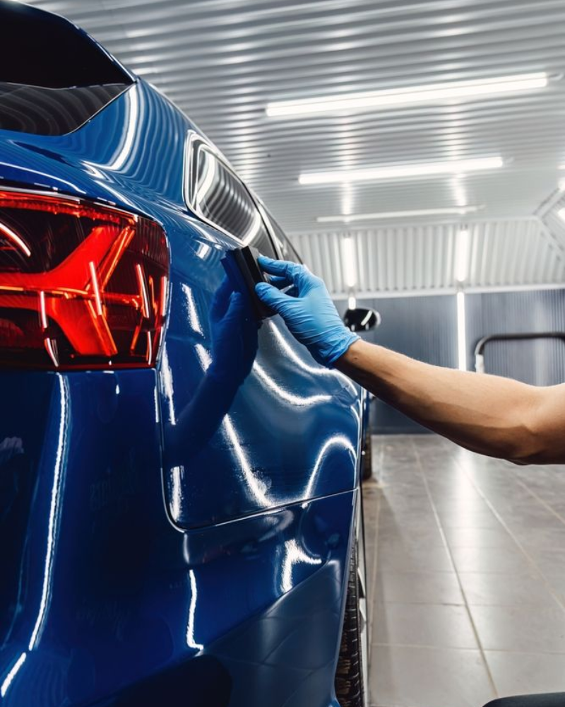 A car is covered in plastic wrap in a garage.