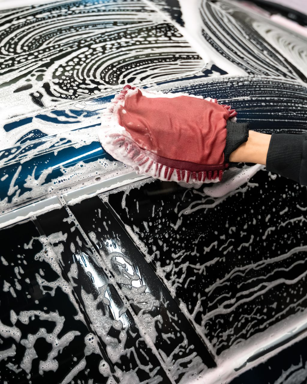 A person is applying a clear film to the hood of a car.