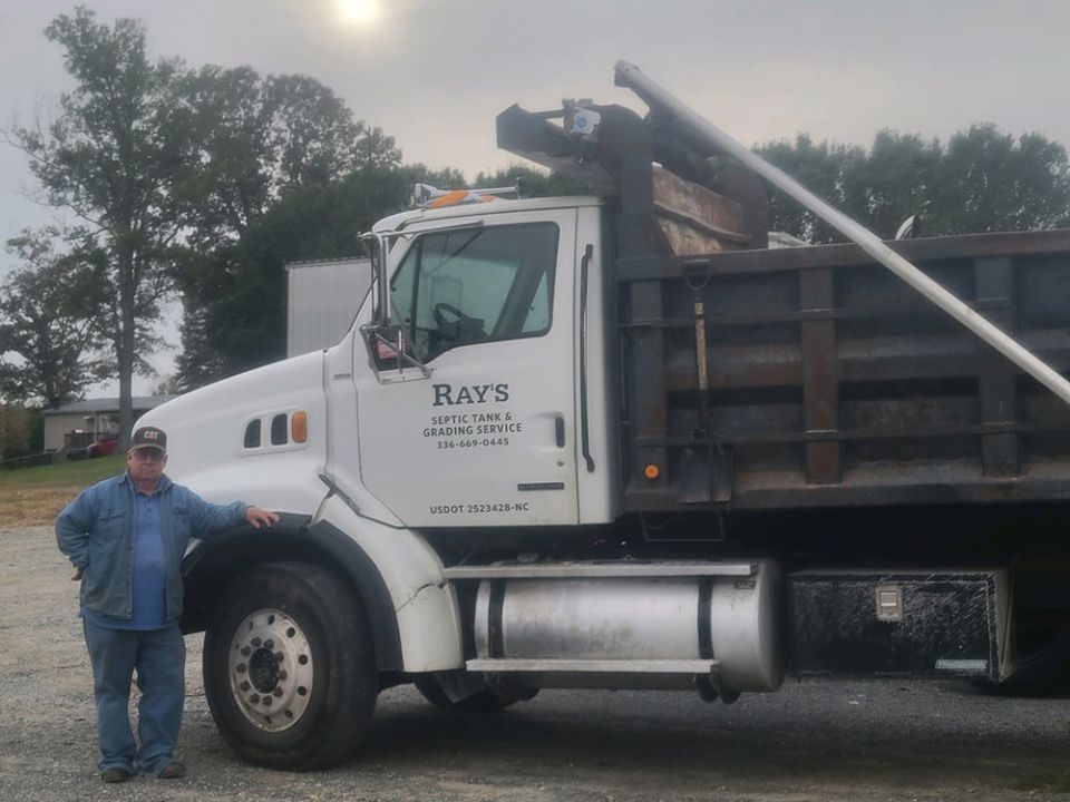 A man standing next to a Ray's Septic truck