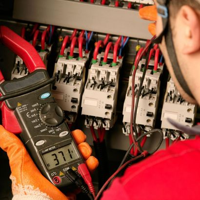 A man is holding a digital multimeter that reads 37.1