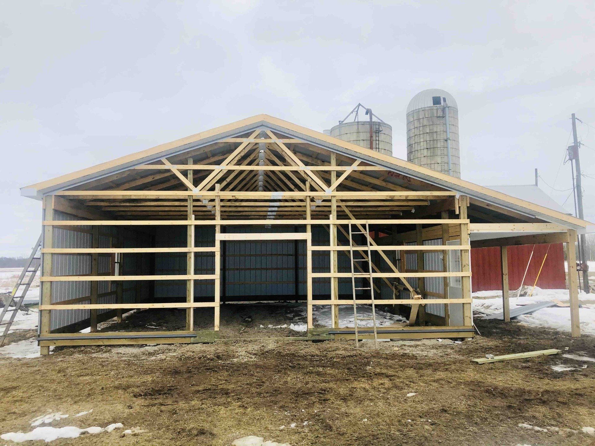 a barn is being built on a farm with silos in the background .