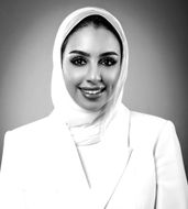 Professional portrait of a woman in a white hijab, smiling.