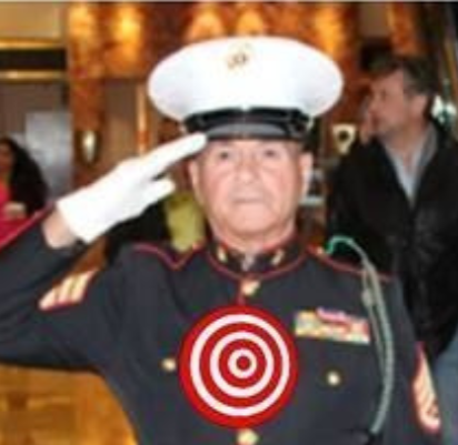 Marine in uniform saluting, with target superimposed over chest; indoors.