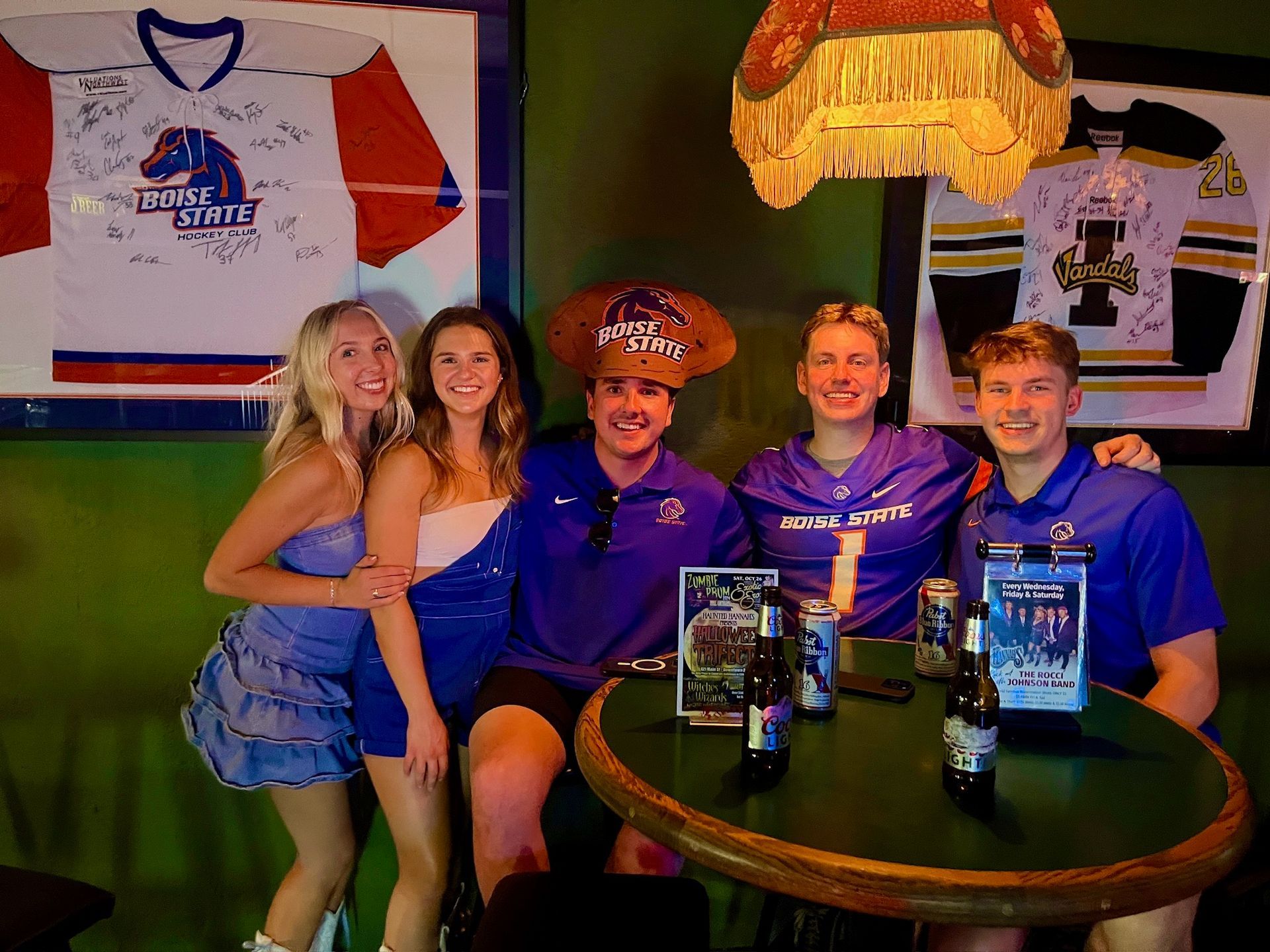 Three women in cowboy hats are sitting at a table in a bar.