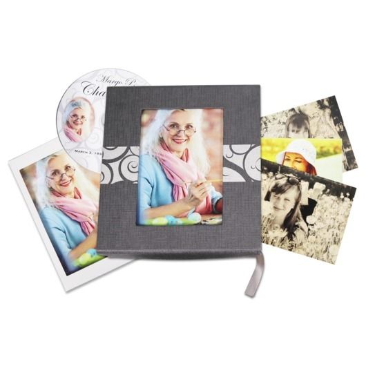 Photo album with a gray cover, colorful portrait photo, and scattered printed photos around it