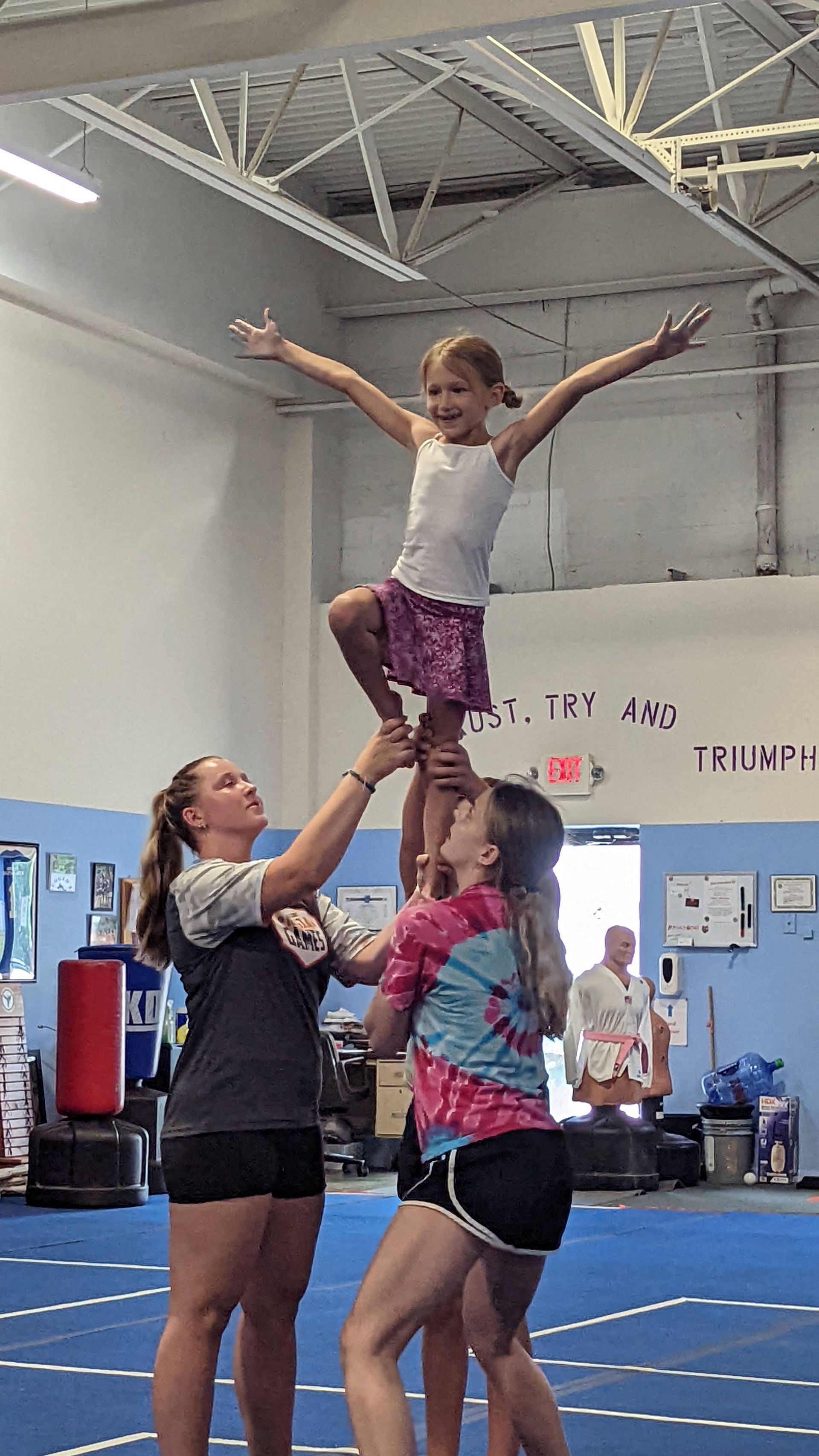 A group of girls are doing a cheer routine in a gym.