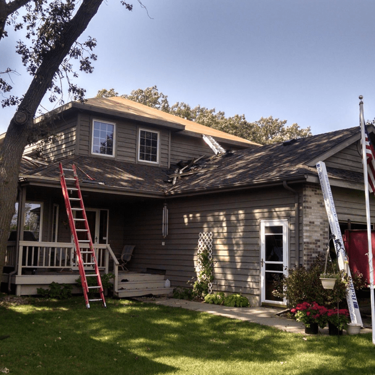 House with a partially replaced roof. A red ladder leans against the siding. A tall white pole stands nearby.