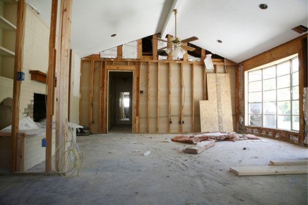 Room under construction with exposed wooden framing and debris on the floor.