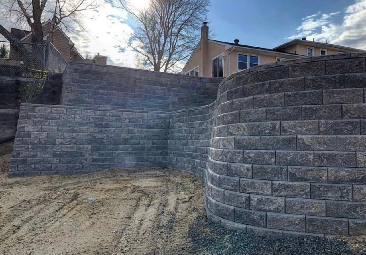Gray brick retaining walls on a sloped yard, near a house.