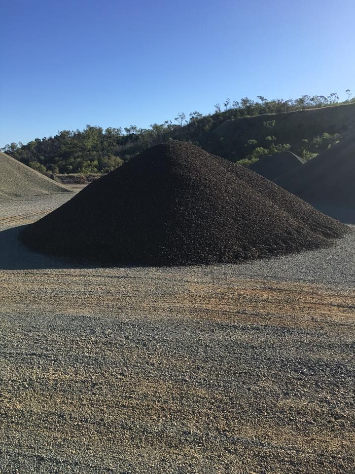A Large Pile of Dark Gray Rocks Against a Hillside, Under a Blue Sky — The Caves Quarry CQ in The Caves, QLD