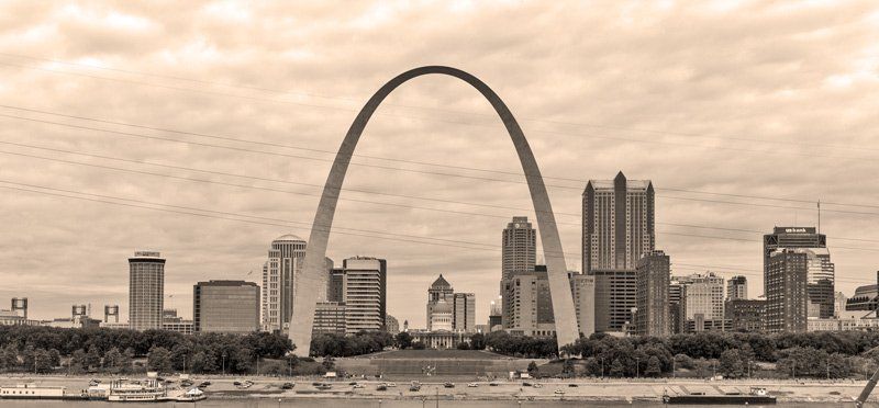 a black and white photo of a city skyline with the st. louis arch in the foreground . Gateway Arch, viewed from East St. Louis shore, sepia, Leica M10 with Voightlander 35mm f1.2 lens