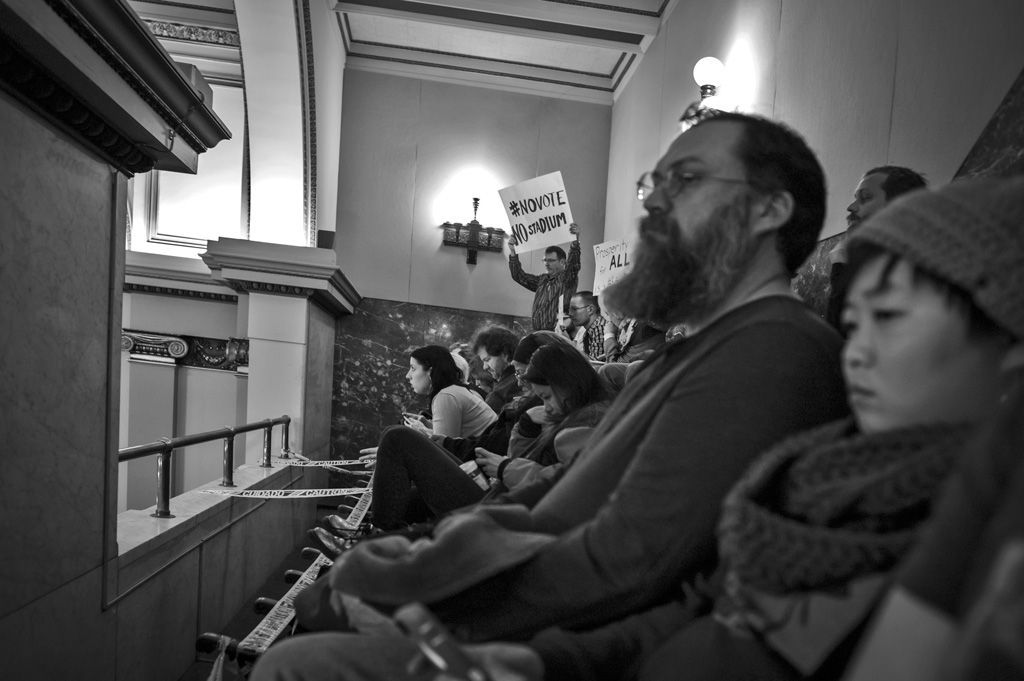During a controversial Stadium vote at City Hall. Protesters sit in the dangerous second floor gallery overlooking the Board of Aldermen proceedings to protest a procedural matter that would deny citizen comments to keep and pay for a football stadium in downtown St. Louis, built by the St. Louis Rams NFL team, but abandoned when they moved to Los Angeles in 2015. Citizens did not want to be shackled with extra corporate debt by Rams owner Stan Kroenke. Photographed on December 15, 2015.