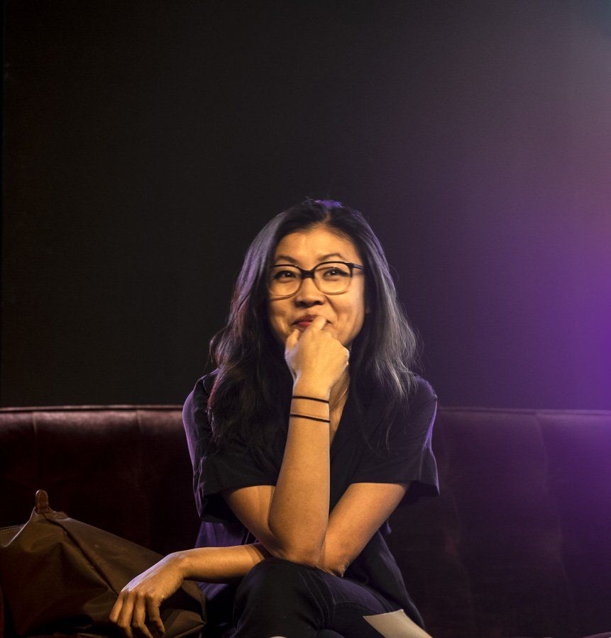 a recently published young novelist  wearing glasses is sitting on a couch with her hand on her chin just before an author talk at the 2018 Central West End Book Fair sponsored by local bookstore Left Bank Books of St. Louis, Missouri.