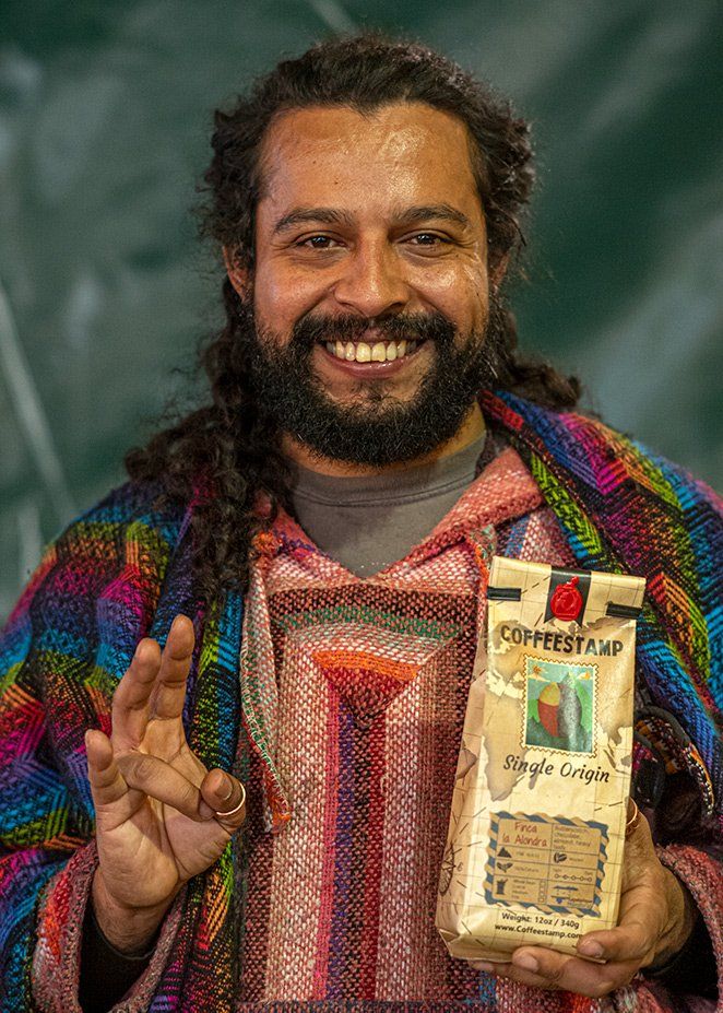 Spencer Clapp, co-owner of Coffeestamp coffee houses and roasters in St. Louis, Missouri, a man with a beard is holding a bag of coffee and smiling .