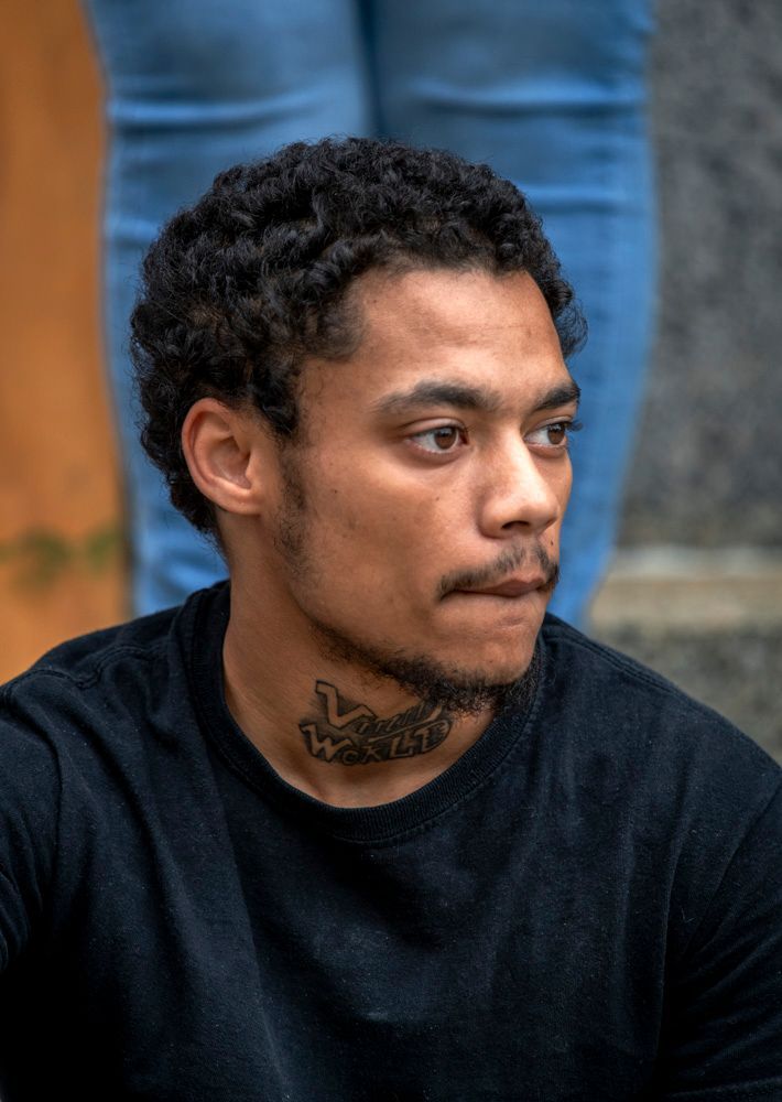 a man has a tattoo on his neck that says waste, sitting in front of the civil courthouse in downtown St. Louis participating in a memorial for a friend who was killed by police in an act of fatal state violence. Victim was unarmed and in his home during a swat team warrantless search.
