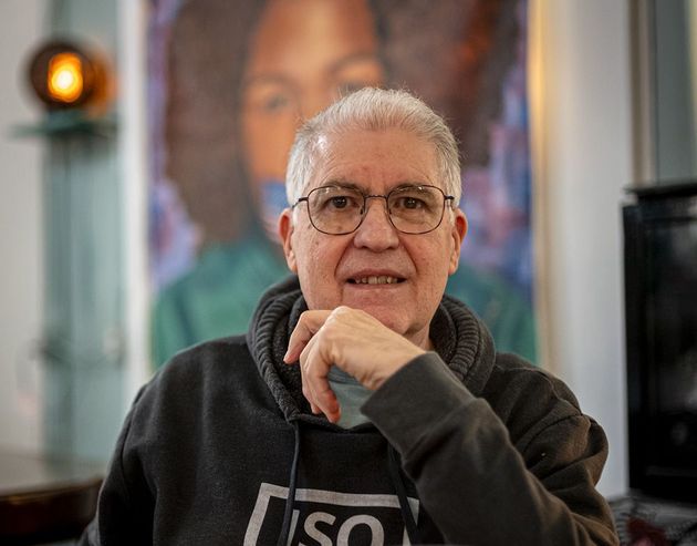 Chuck Ramsay,photographer, wearing glasses and a hoodie and sitting in front of a painting. Photo by John Montre using Chuck's Leica M10 and Voightlander 35mm f1.2 lens in The Drip Community Coffee House, St. Louis, MO. Chuck is a retired corporate communications professional who served as the Communications Director for the Bar Association of Metropolitan St. Louis prior to his retirement in 2015, among other companies and industries for over 45 years.