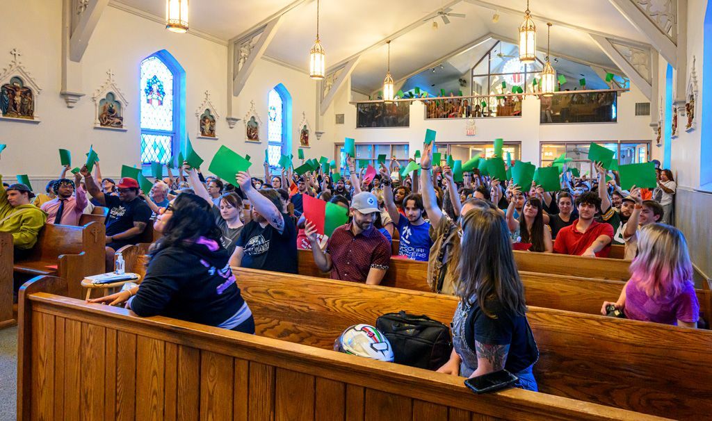 Attendees of the data center town hall meeting at Saint Cronin’s Catholic Church in The Grove neighborhood voted on key issues by raising either green sheets of paper for YES or red sheets for NO. Key issues included acceptability of higher electricity bills that result when data centers use huge amounts of power, but utilities spread the cost across their entire customer base; increased pollution to the environment from greater use of making of that electricity, and pressure on water resources needed to cool the machinery of a data center. These impacts were seen as negative when weighed upon narrow benefits from the companies operating data centers. Photographed October 12, 2025. 