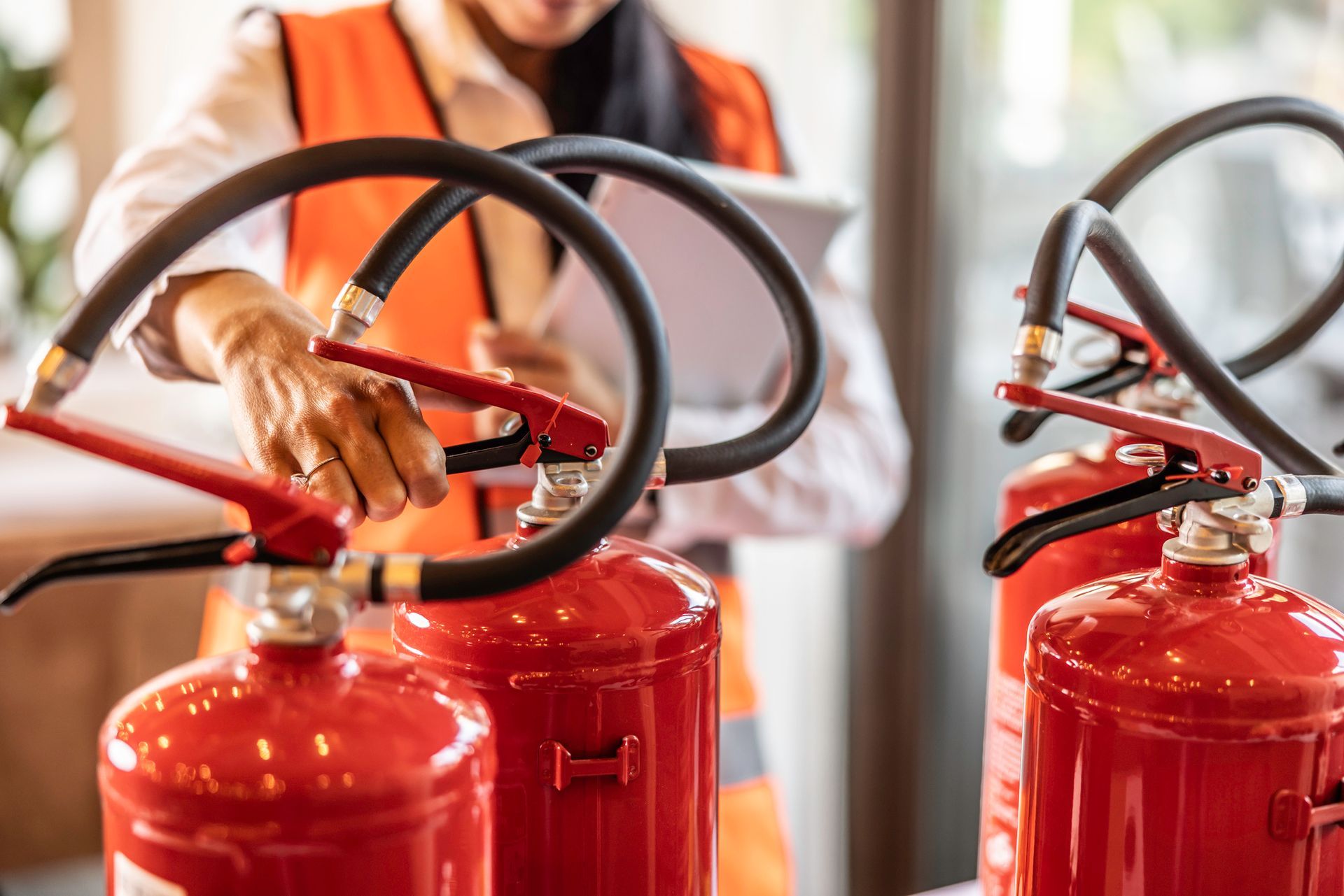 A woman is inspecting fire extinguishers.