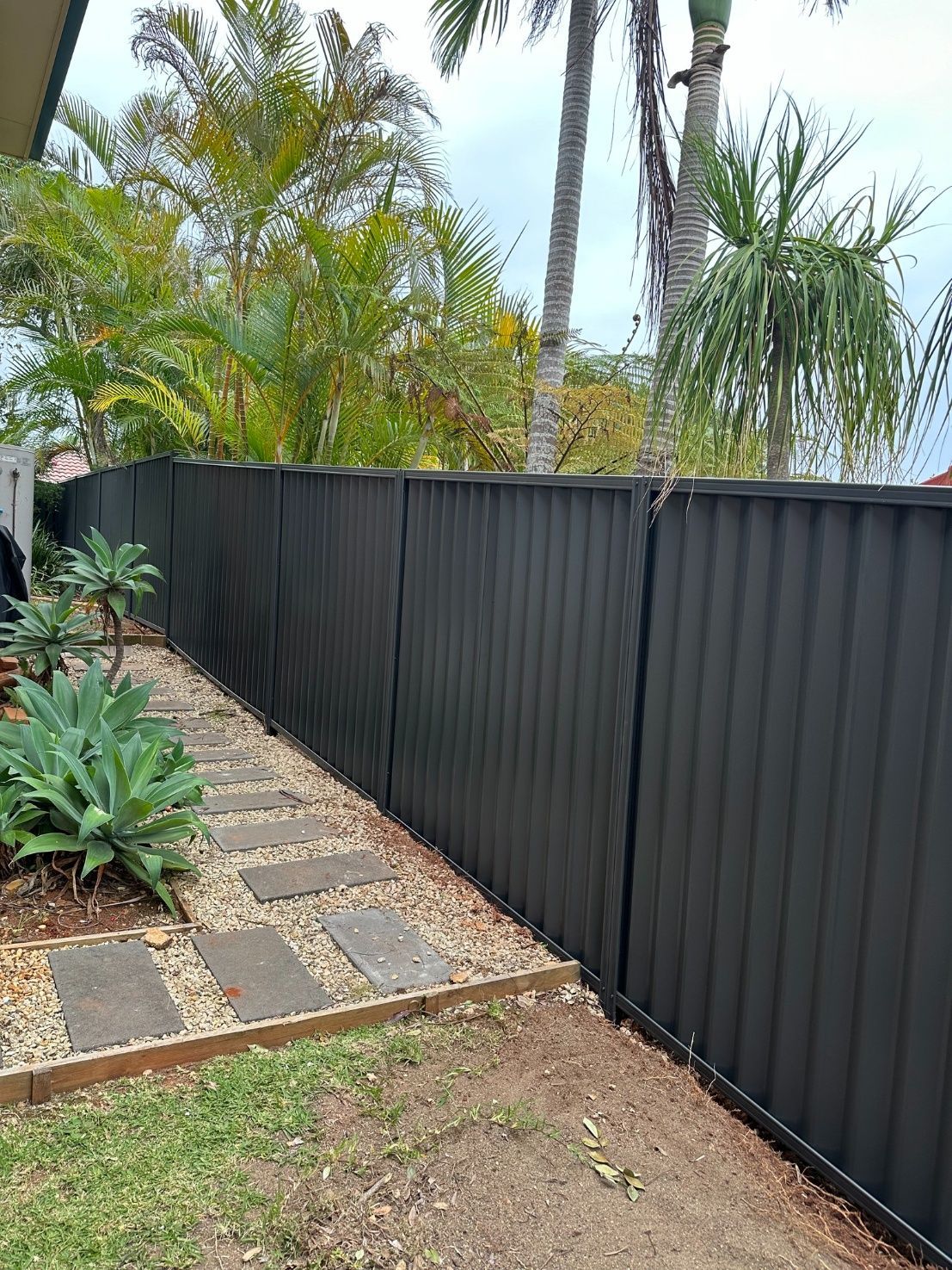 A Gray Gate Is Sitting In Front Of A Brick Building — Mid Coast Boundary Fencing In Harrington, NSW