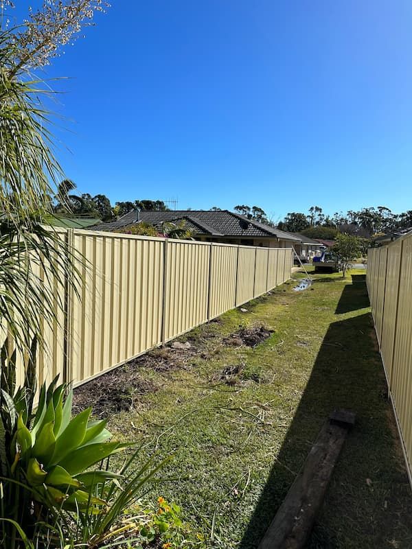 A Fence Surrounds A Lush Green Yard — Mid Coast Boundary Fencing In Old Bar, NSW