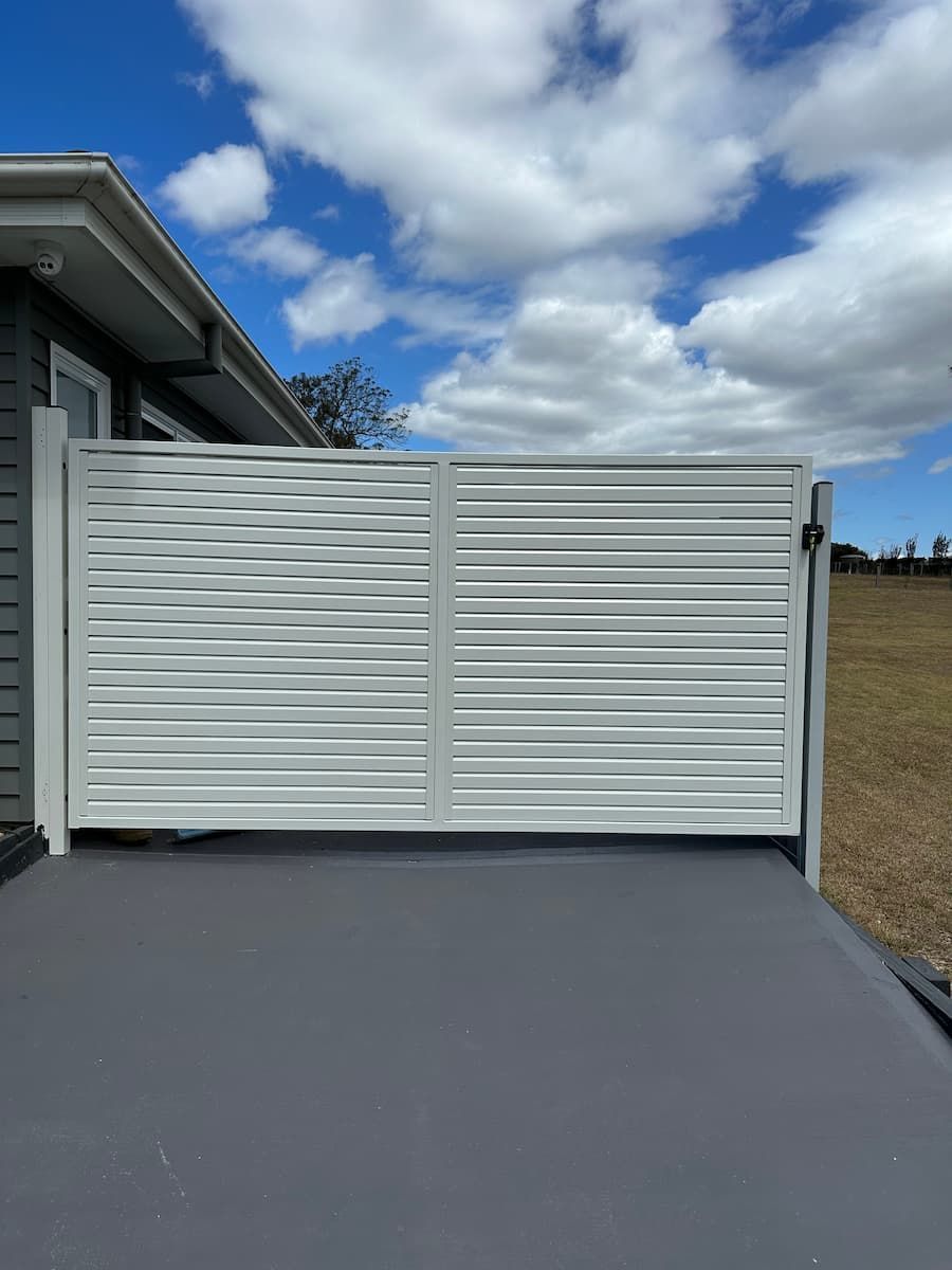 A White Gate Is Sitting In Front Of A House — Mid Coast Boundary Fencing In Old Bar, NSW