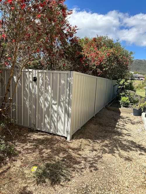 A White Fence With A Gate Is Surrounded By Trees And Bushes — Mid Coast Boundary Fencing In Old Bar, NSW