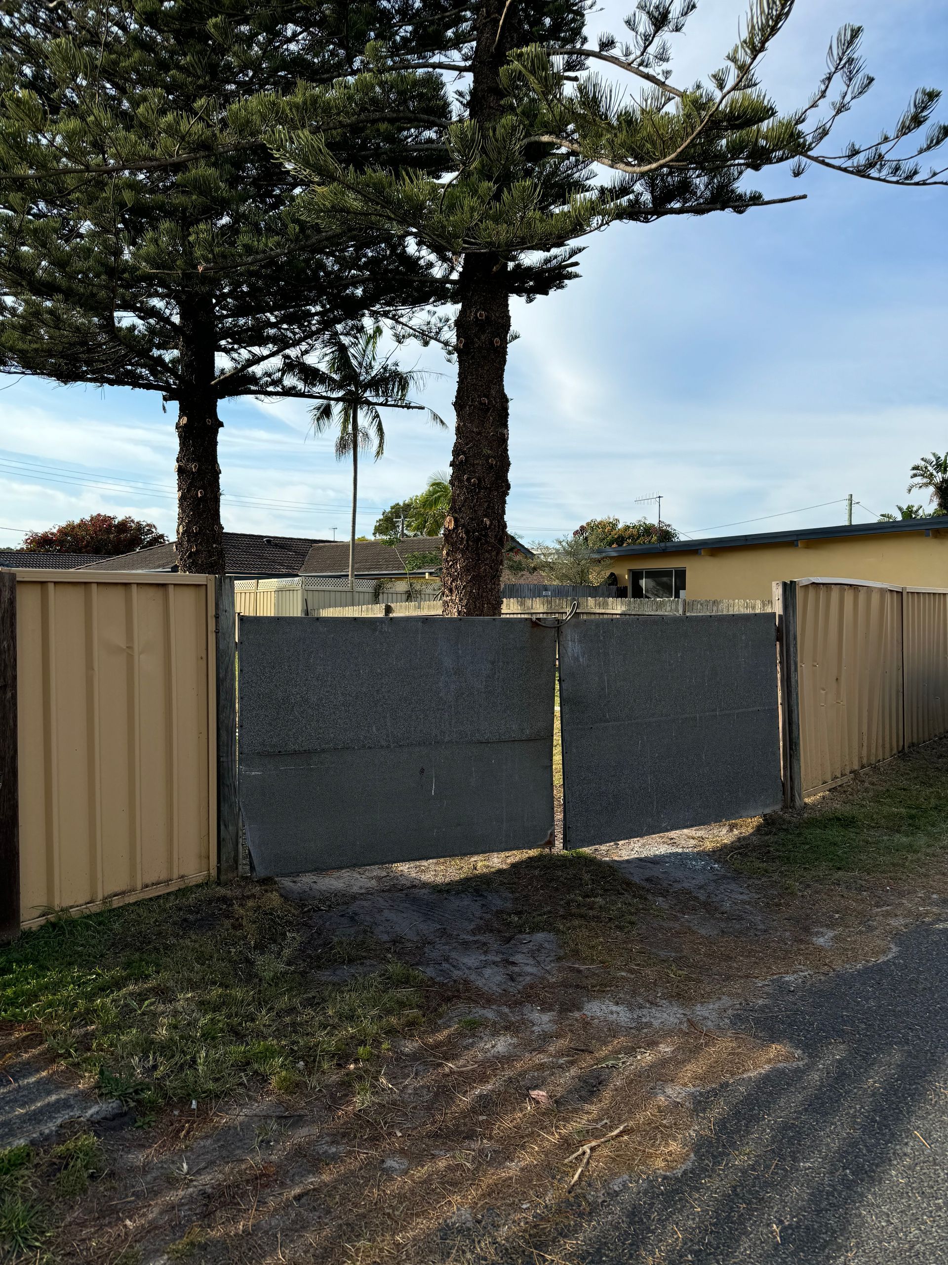A Wooden Fence Is Surrounded By Grass And A House In The Background — Mid Coast Boundary Fencing In Old Bar, NSW