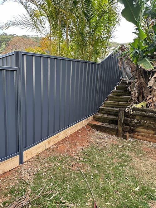 A Fence With Stairs Leading Up To It In A Backyard — Mid Coast Boundary Fencing In Old Bar, NSW