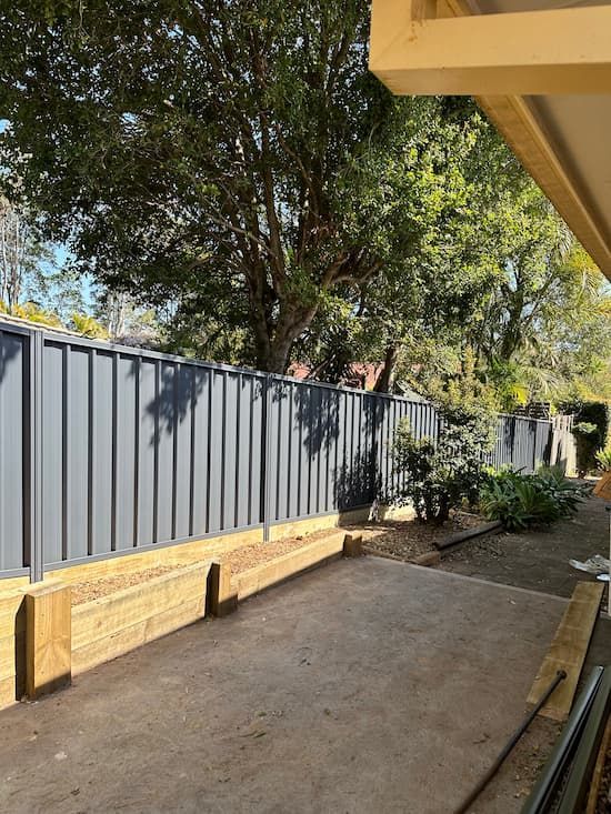 There Is A Fence In The Backyard With Trees In The Background — Mid Coast Boundary Fencing In Old Bar, NSW