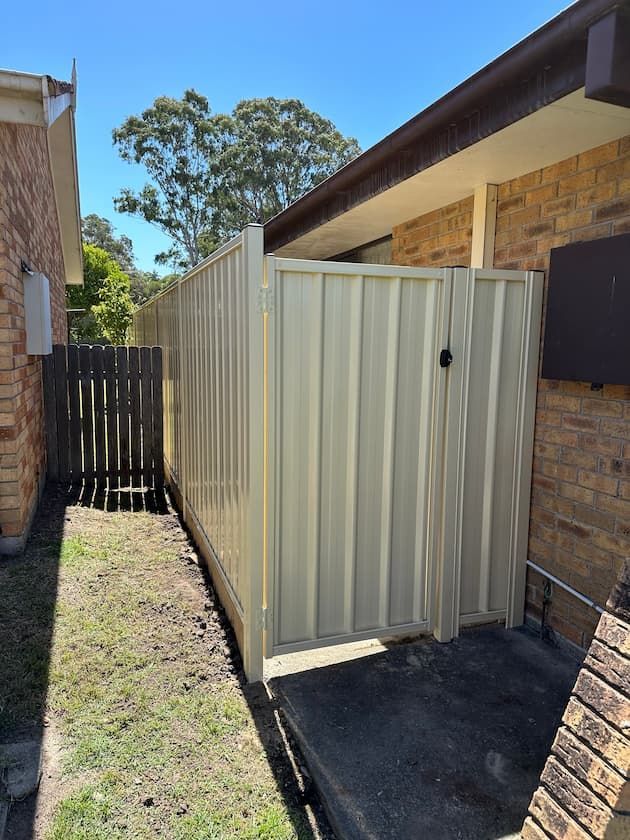 A White Fence With A Gate In The Backyard Of A House — Mid Coast Boundary Fencing In Old Bar, NSW