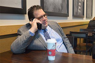 Attorney Daniel Talking Into A Phone Whit Coffee On A Table - Grosse Pointe Farms, MI - Dodson Fowler Williams & Nesi