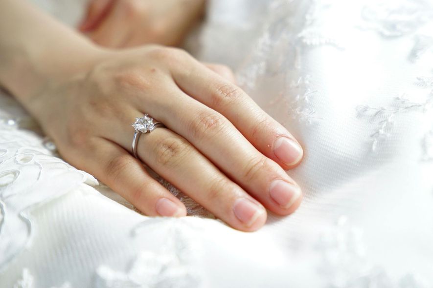 A close up of a woman 's hand with an engagement ring on it.