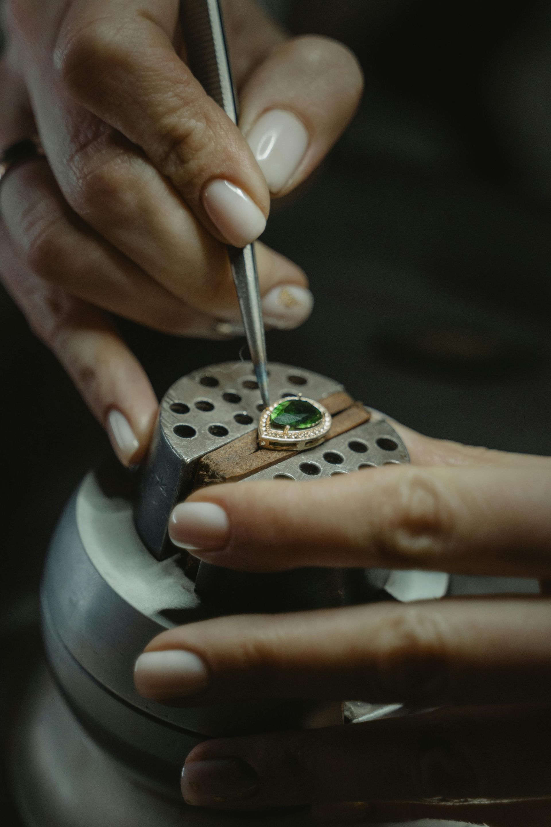 A close up of a person 's hands working on a piece of jewelry.