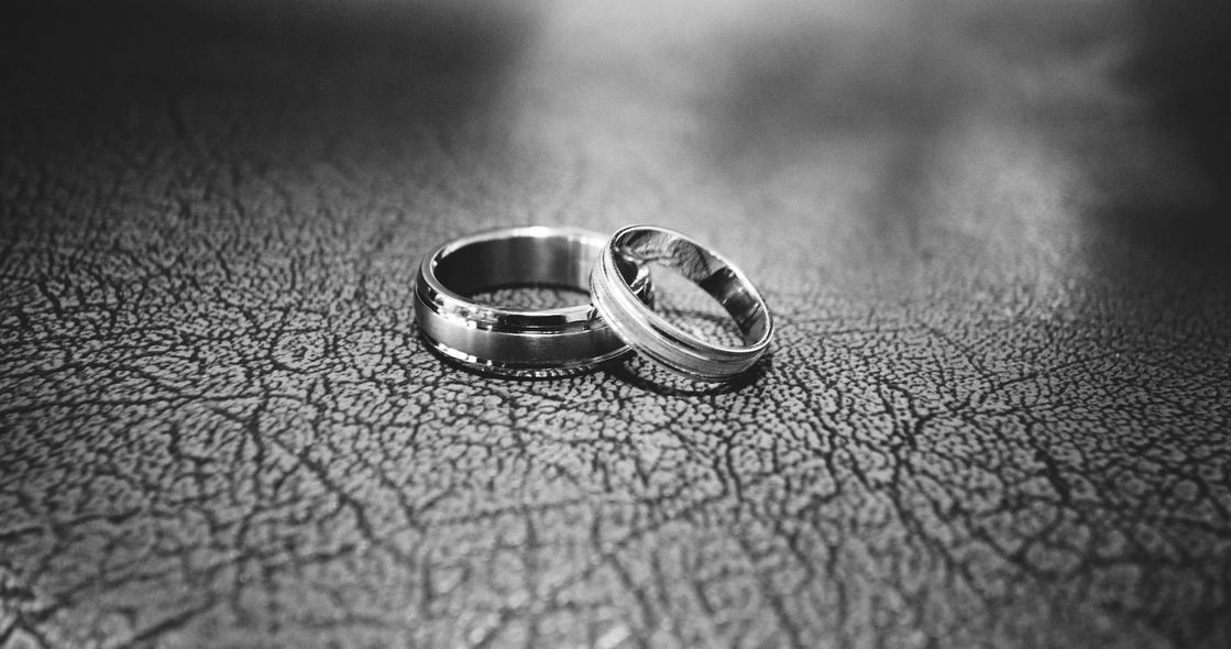 Two wedding rings are sitting on a cracked surface.
