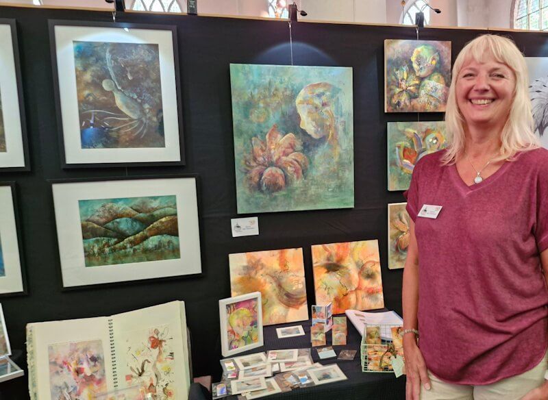 Joyce van Paassen bij haar stand tijdens de expositie in de Grote Kerk (Kunst festival Onder de Linden Vlaardngen)