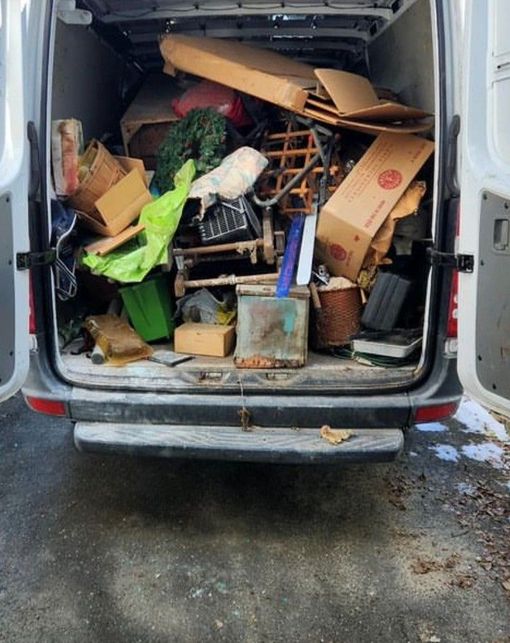 Open rear of a van filled with assorted junk and discarded items.