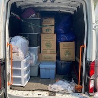 Interior of a moving van filled with boxes, plastic bins, and bags, likely containing household items.
