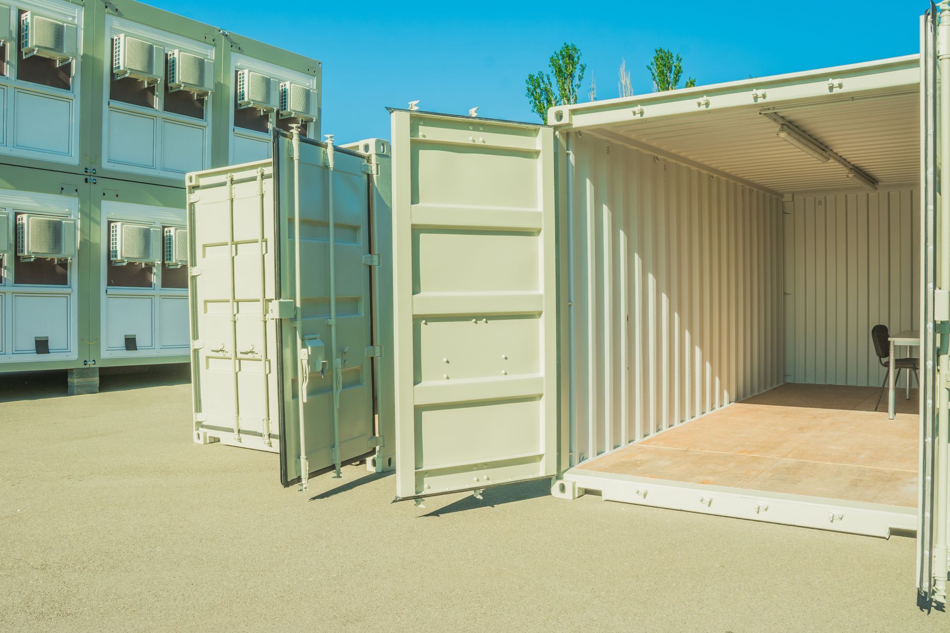 Cluttered room with stacked cardboard boxes, baskets, and miscellaneous items near a window.