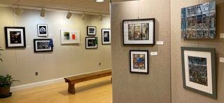 Art gallery with paintings on white walls, geometric ceiling, people viewing artwork.