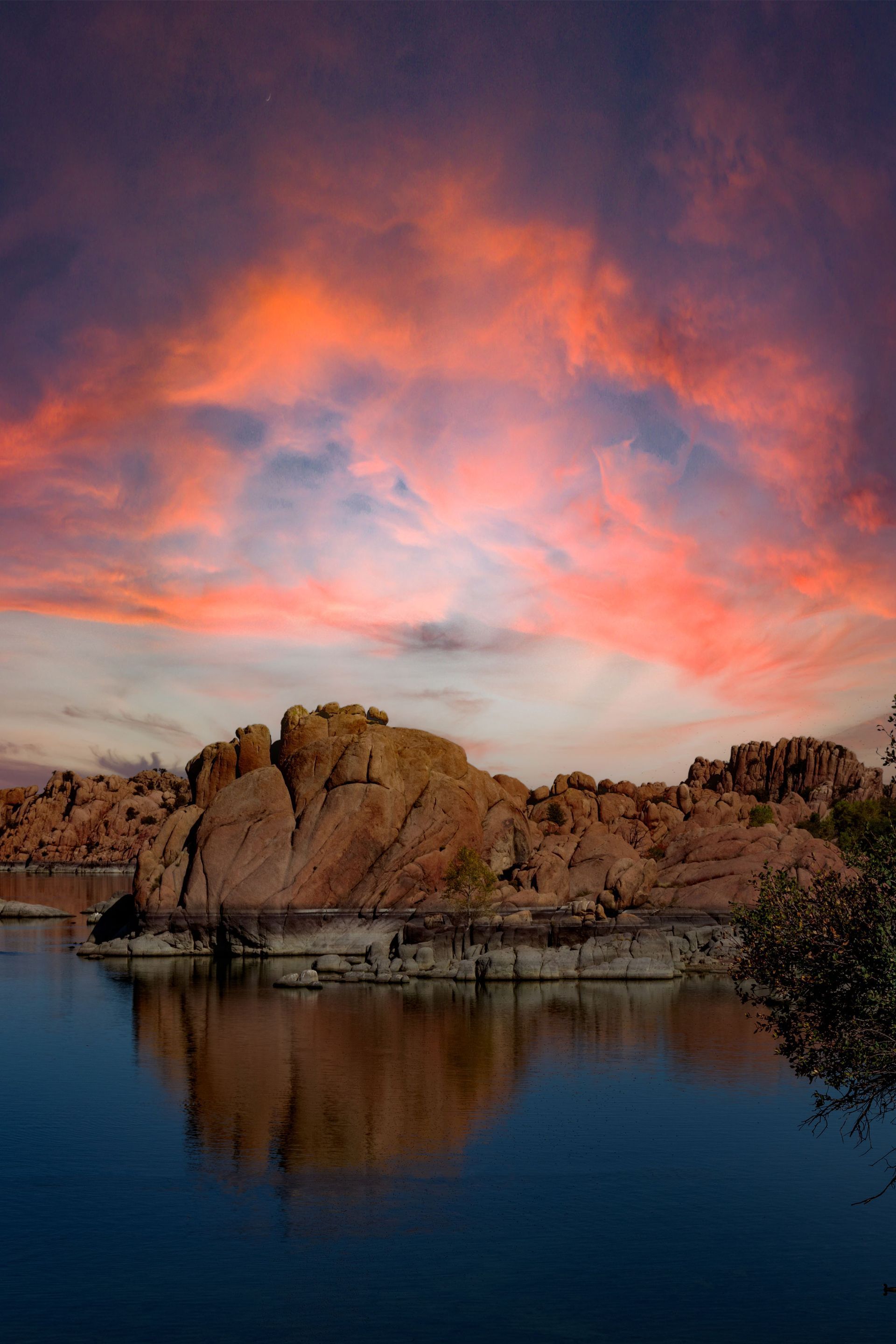 A sunset over a lake with rocks in the foreground