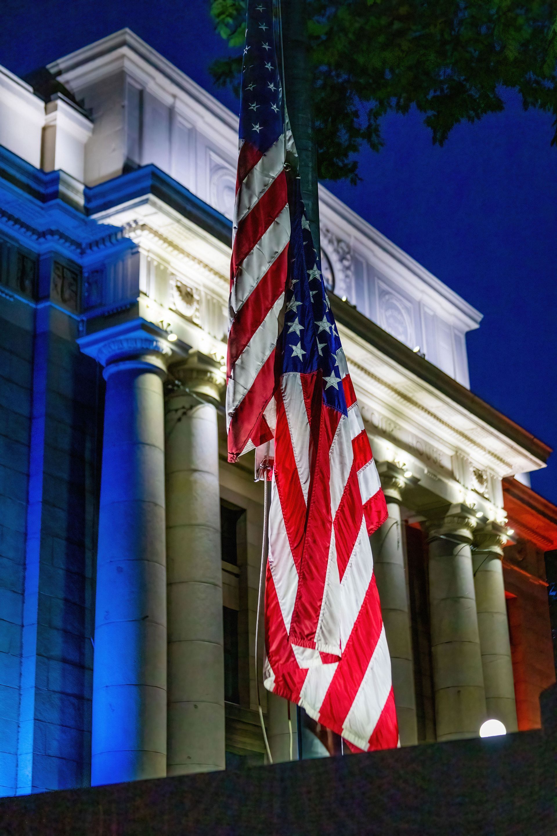 An american flag is flying in front of a building at night