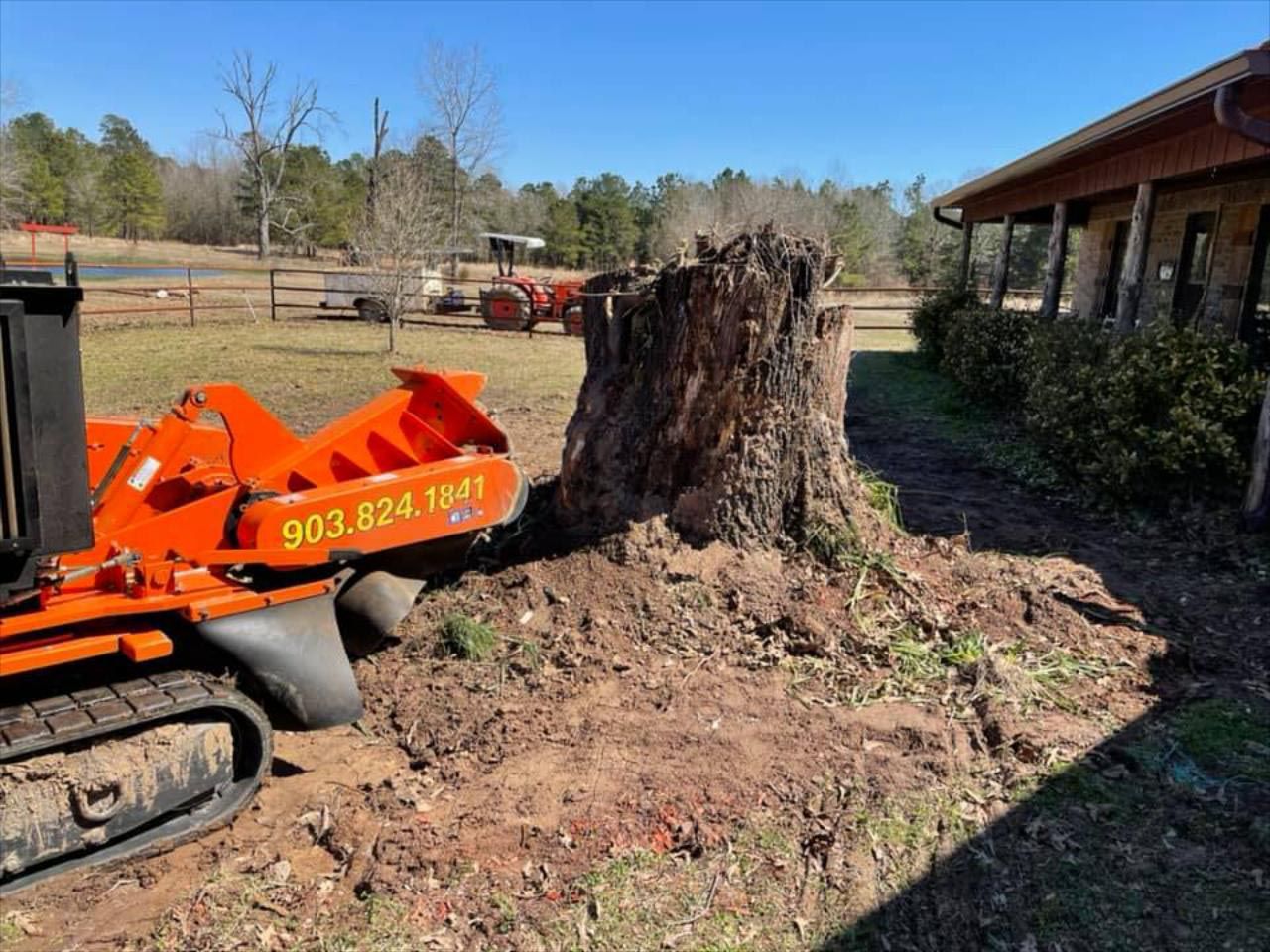 A large tree stump is being removed by a tractor.