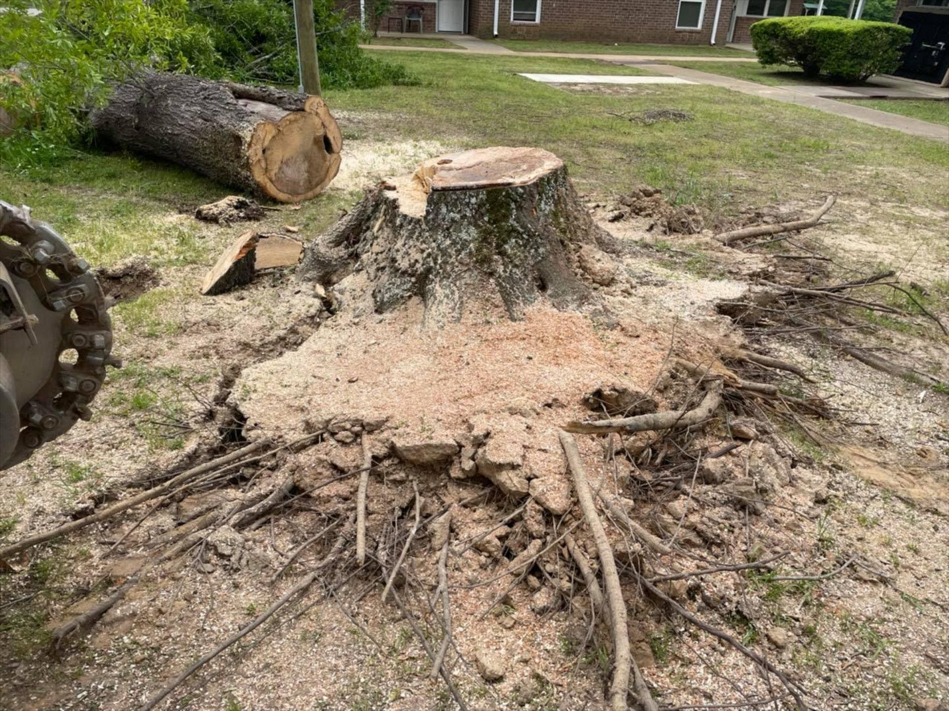 A tree stump is being removed by a machine in a yard.
