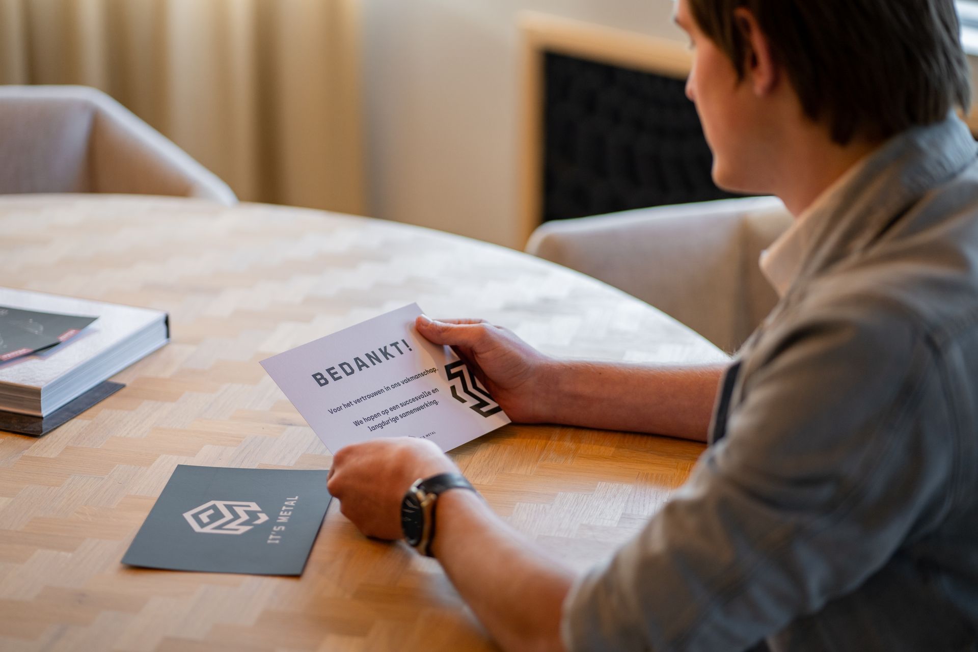Een man zit aan een tafel en schrijft op een stuk papier.