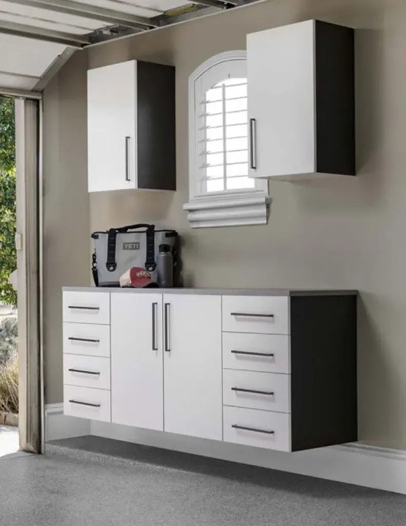 A garage with white cabinets and drawers and a window.