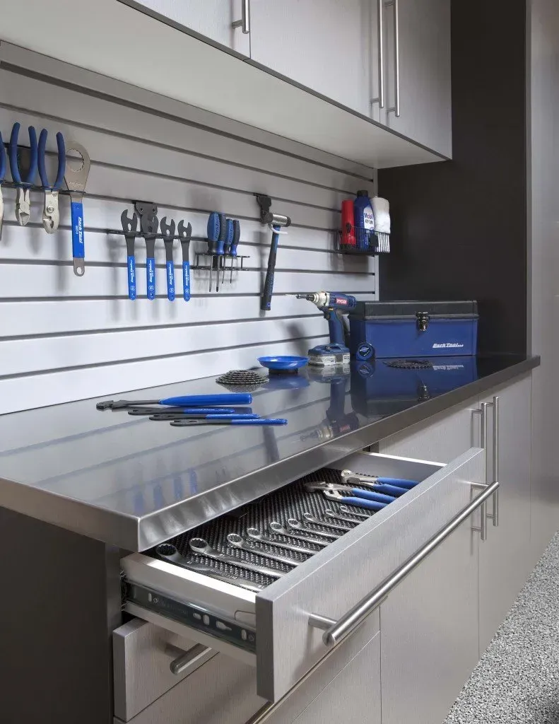 A stainless steel workbench with a drawer full of tools