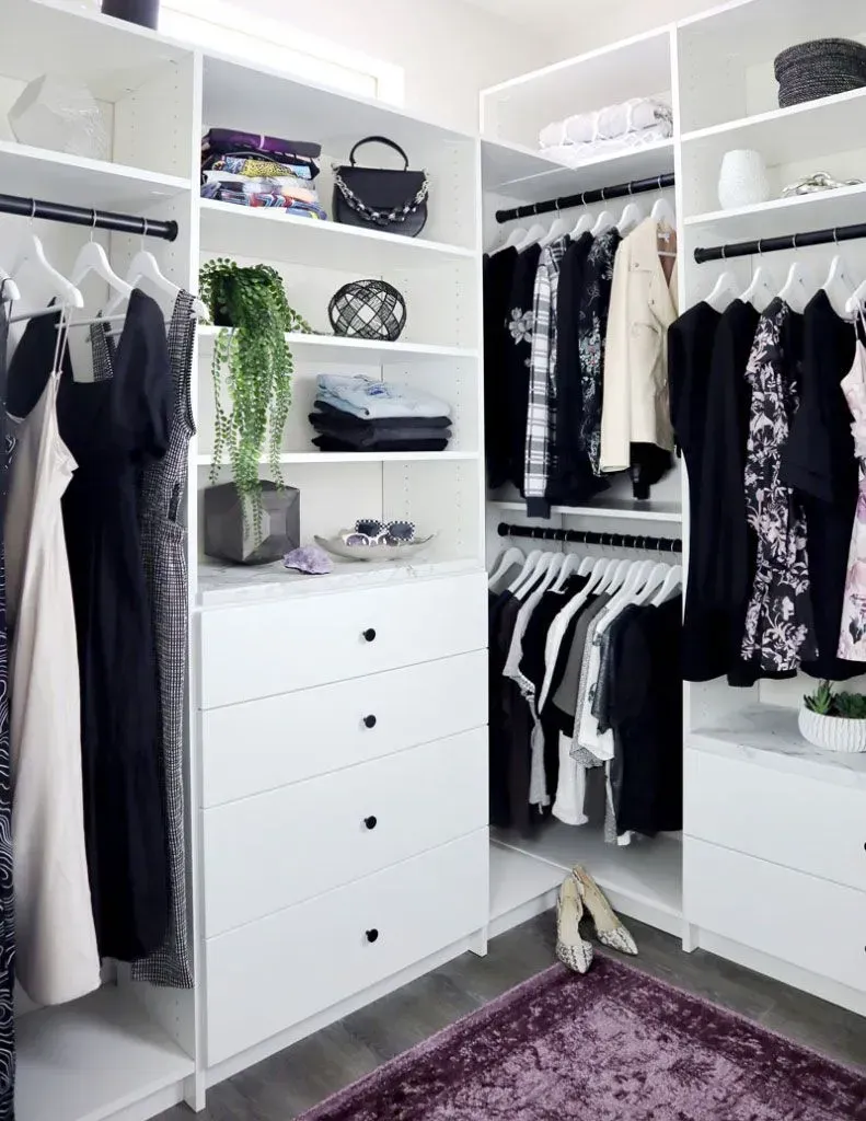 A walk in closet filled with clothes and a purple rug.